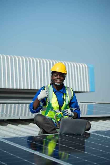 Solar technician giving a thumbs-up while installing panels on a Nigerian rooftop